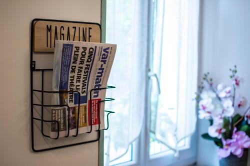 un portarevistas en una pared junto a una ventana en Hotel Le Flore en Fréjus