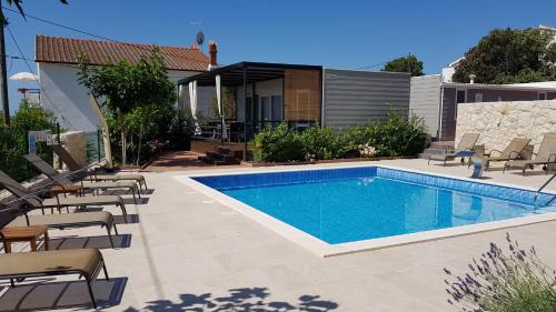 a swimming pool with chairs and a house at Villa Anka in Rab