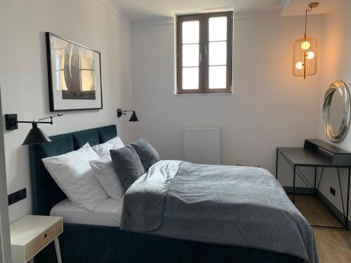 1 dormitorio con cama azul y almohadas blancas en Apartamenty - Przy Ratuszu en Sandomierz