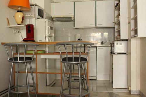 Una cocina con gabinetes blancos y taburetes de bar. en STUDIO STANDING BORD DE MER ET VUE, en Antibes