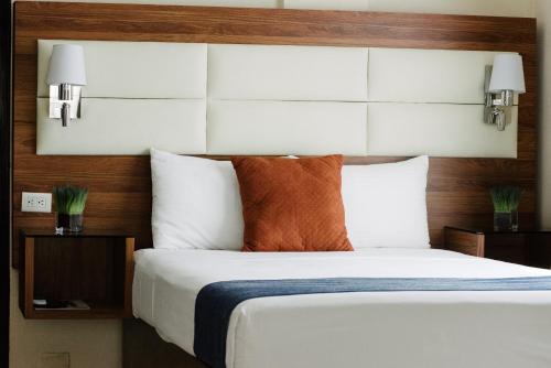 a bedroom with a large white bed with wooden headboard at Hotel San Miguel, en el Centro - Desayuno Incluido in Tuxtla Gutiérrez