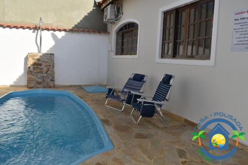 Una piscina en un patio con sillas y un edificio. en Hostel Bike Point Caraguatatuba, en Caraguatatuba