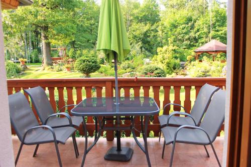 a table with chairs and an umbrella on a porch at Dom Natury in Karpacz