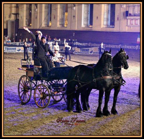 a man is waving while riding in a horse drawn carriage at OSTELLO DI SAN GERMANO in Borgofranco dʼIvrea