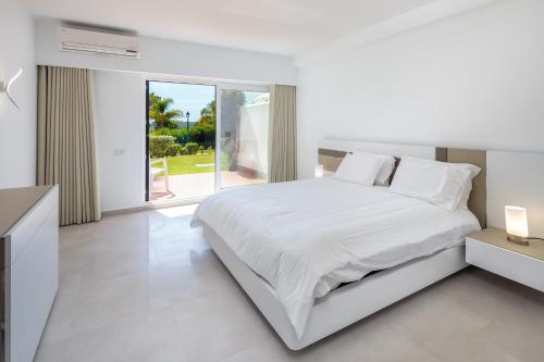 a white bedroom with a white bed and a window at Victory Village Sea Views in Quinta do Lago