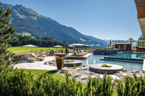 a resort with a swimming pool and a mountain at Hotel Plunhof in Ridanna