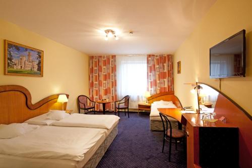 a hotel room with two beds and a table at Hotel Savoy in České Budějovice