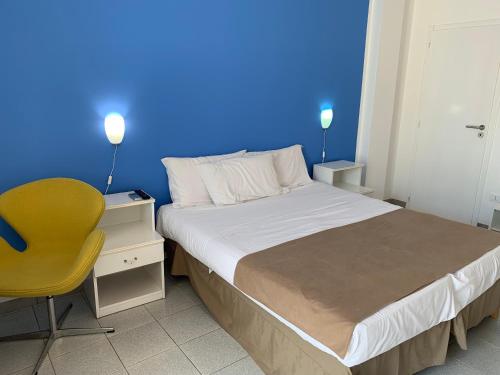 a bedroom with a blue wall and a bed and a yellow chair at Guest House - La Sirena Salentina in Patù