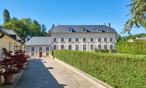 a large house with a hedge in front of it at Moulin Royale in Saint-Etienne-Roilaye