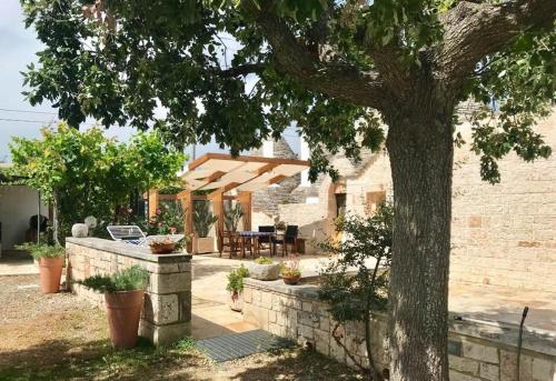 une terrasse avec un arbre en face d'une maison dans l'établissement Trulli di Pozzomasiello, à Locorotondo