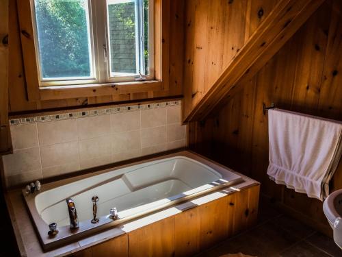 a bath tub in a wooden bathroom with a window at Auberge Couleurs de France in Lac-Simon
