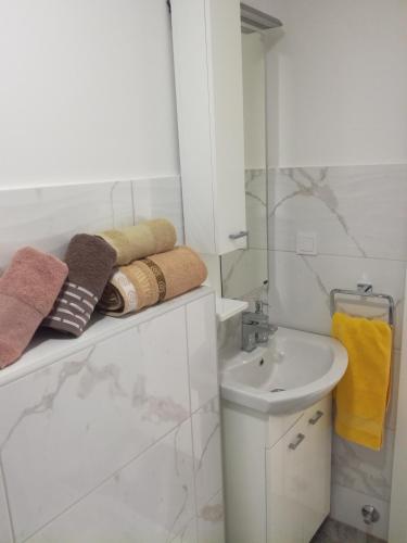 a white bathroom with a sink and towels on a shelf at Olea in Tivat
