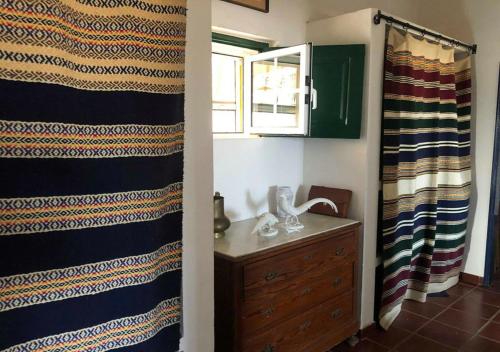 a bathroom with a shower curtain and a wooden dresser at Monte da Figueira in Amareleja