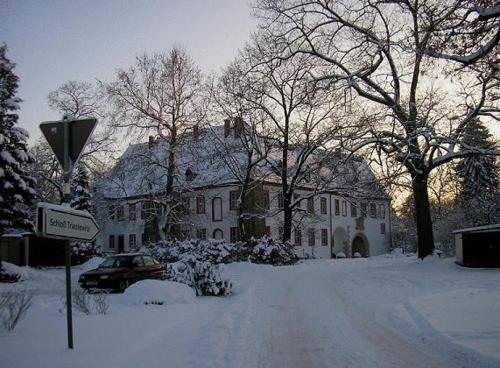 a house is covered in snow with a car parked in front at Schloss Triestewitz in Arzberg