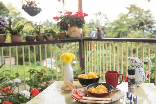 una mesa con un plato de comida y un jarrón con flores en La Posada de La Abuela Salento en Salento