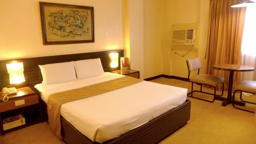 a hotel room with a large bed and a chair at Rothman Hotel in Manila