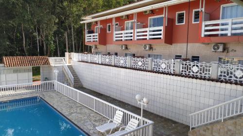 a building with a swimming pool next to a house at Suítes Ubatuba Praia da Lagoinha in Ubatuba