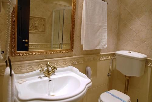 a bathroom with a sink and a toilet and a mirror at Hotel Iva & Elena in Pamporovo