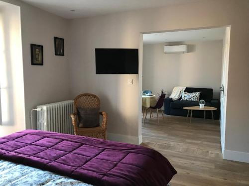 a bedroom with a purple bed and a living room at LA MAISON DE MARION in Tournus