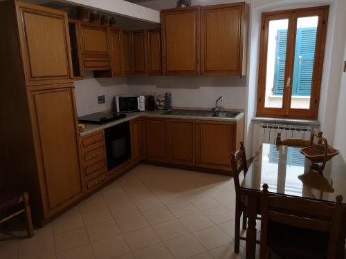 eine Küche mit Holzschränken, einem Tisch und einem Fenster in der Unterkunft Ca' dei Nogi - Appartamento a Riomaggiore in Riomaggiore
