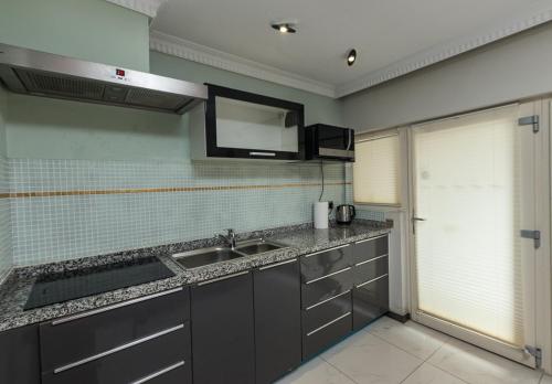 a kitchen with a sink and a tv on the wall at Red Mango Hotel and Apartments in Takoradi