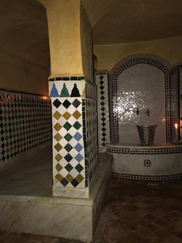 um quarto com uma coluna com azulejos coloridos em Ryad Bahia em Meknès