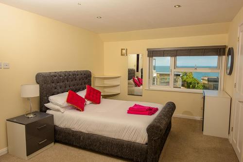 a bedroom with a bed with red pillows on it at Cliff Top Apartment 3 Bedroom in Shanklin