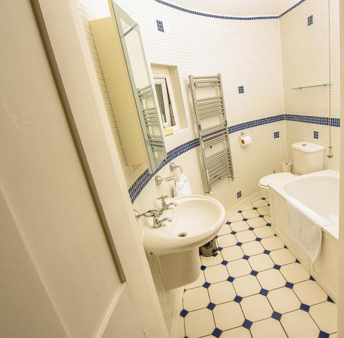 W łazience znajduje się umywalka, toaleta i lustro. w obiekcie Cliff Top Apartment 3 Bedroom w mieście Shanklin