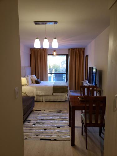 a bedroom with a bed and a desk and a window at URBANA SUITES & STUDIOS 440 in San Carlos de Bariloche