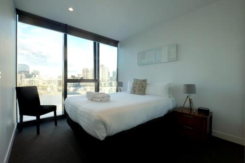 a bedroom with a bed and a chair and a window at ACD Apartments in Melbourne
