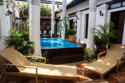 a pool in the middle of a patio with two chairs at Aroha Villana Hostel in Santa Marta