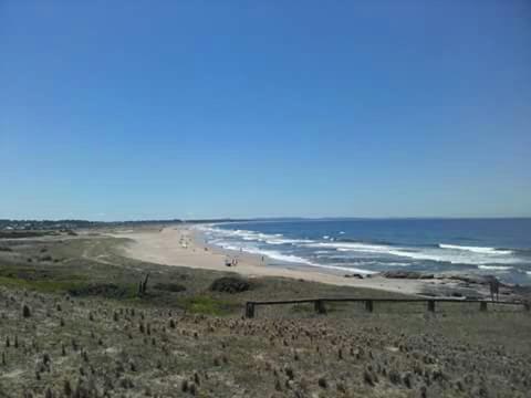 a beach with people walking on the sand and the ocean at Mar y Cerros in Piriápolis