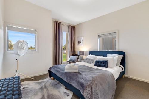 Un dormitorio con una cama azul y blanca y una ventana en Tangles, en Ballarat