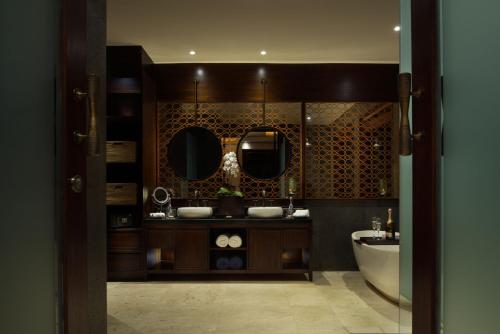 a bathroom with two mirrors and a sink and a tub at Samsara Ubud in Ubud
