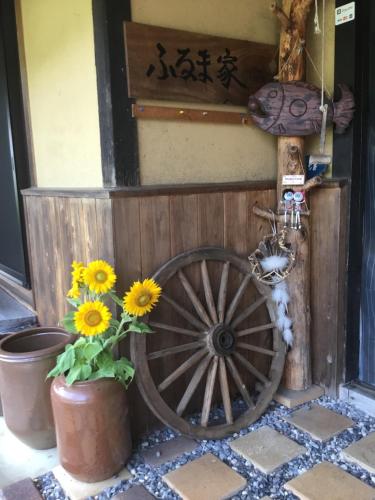 a wheel and flowers in front of a building at 古民家の宿 ふるま家 Furumaya House Gastronomic Farmstay in Deep Kyoto in Fukuchiyama