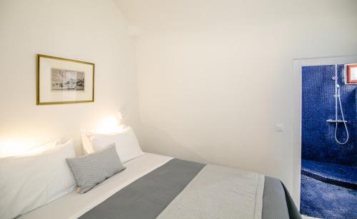 a bedroom with a white bed and a blue shower at Aloia Villas in Oia