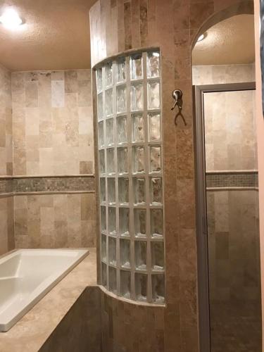 a bathroom with a tub and a glass block wall at BELLA SIRENA RESORT in Puerto Peñasco