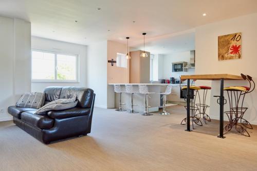 een woonkamer met een leren bank en een keuken bij Le Rayon de Soleil - appartement 2 chambres 90m2 in Saint-Brieuc