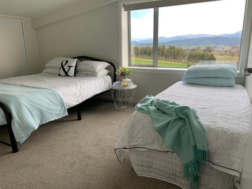 two beds in a room with a large window at Mariri Heights Tasman in Upper Moutere