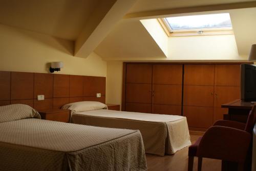 a hotel room with two beds and a skylight at Gran Hotel Balneario in Baños de Montemayor