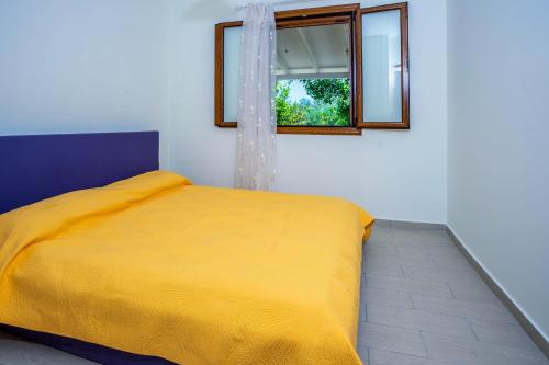 żółte łóżko w pokoju z oknem w obiekcie Lefkada Family friendly house with parking ,yard w mieście Nydri