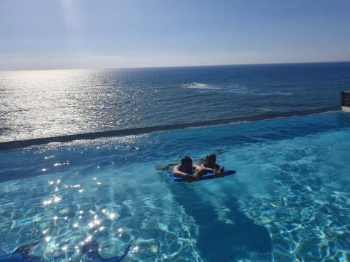 zwei Menschen sitzen auf einem Floß im Wasser in der Unterkunft Beach Villa Pantheon in Pomos