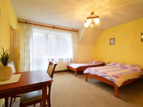 a bedroom with two beds and a table and a window at Villa Mariano Michałowice in Piechowice