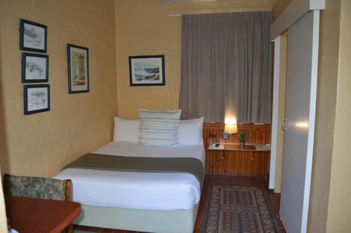 Habitación de hotel con cama y ventana en Ascot Inn en Pietermaritzburg