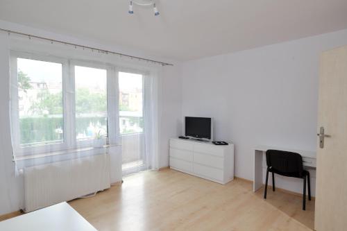 Sala de estar blanca con TV y silla en Apartament Słoneczny 3, en Opole