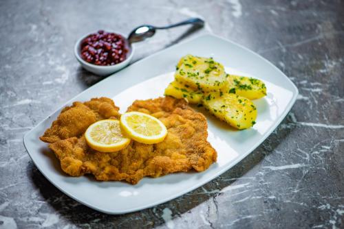 a plate of food with fish and potatoes and lemon slices at Hotel Steinerwirt1493 in Zell am See