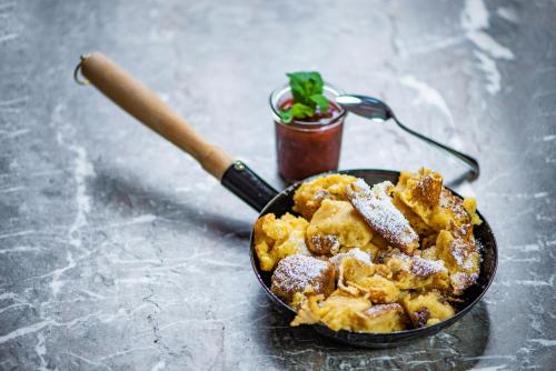 a frying pan filled with fried food and a knife at Hotel Steinerwirt1493 in Zell am See