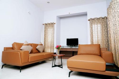 Sala de estar con 2 sofás naranjas y TV en UNNATHI SUITES, en Mysore