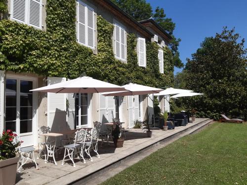 a patio with tables and umbrellas in front of a house at Chambres d'Hôtes Domaine du Hameau Baylesse in Saint-Jean-dʼAigues-Vives