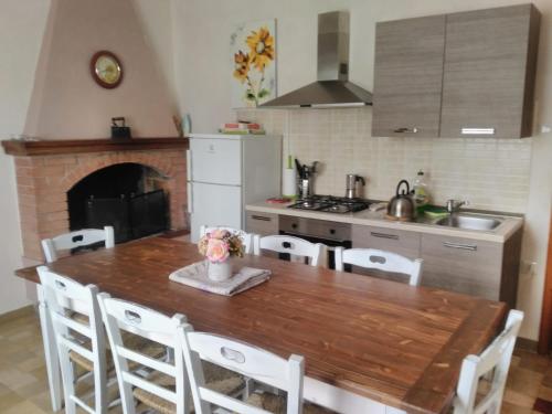 een keuken met een houten tafel met stoelen en een open haard bij Casa Vacanze Garofoli in Genga